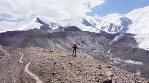 4K fly away drone video of lonely climber in mountaineering gear with backpack a Видео 340110372