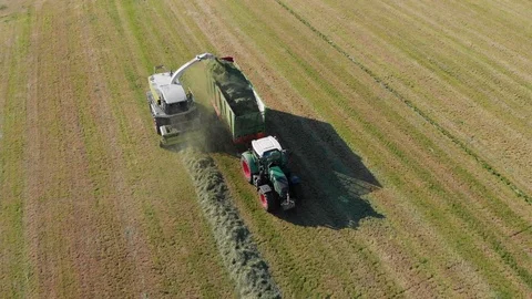 [4K] Flying in front of two Tractors collecting grass from field | Aerial Shot Stock Footage 94296559
