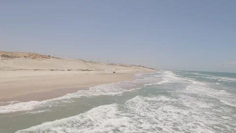4K Flying over sea while seeing jeeps racing on the beach Stock Footage 85912684
