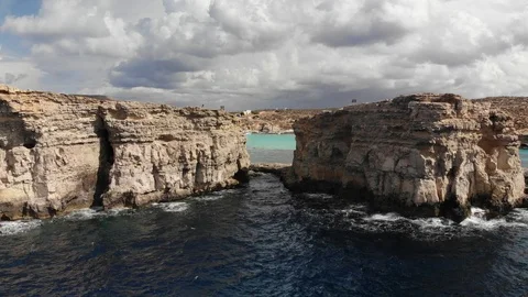 4K flying through rock formation to reveal Malta's blue lagoon and blue water Stock Footage 103170585