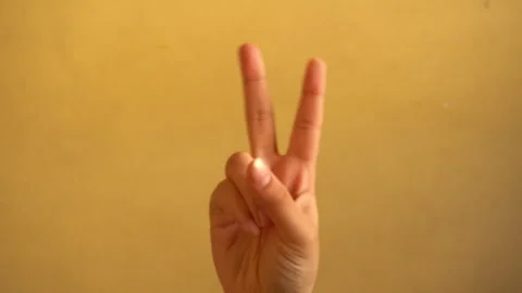 4K footage of a human hand making a peace sign against a simple background. Stock Footage 342702622