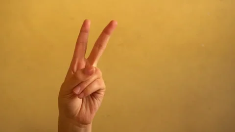 4K footage of a human hand making a peace sign against a simple background. Stock Footage 342702748