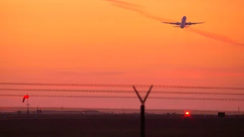 4K footage of twin engine jet plane taking off against an orange sky sunset Video stock 83906363