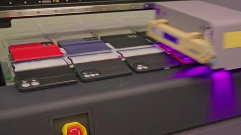 4K footage of a UV printer printing an image on ten mobile phone cases. Stock Footage 328494062
