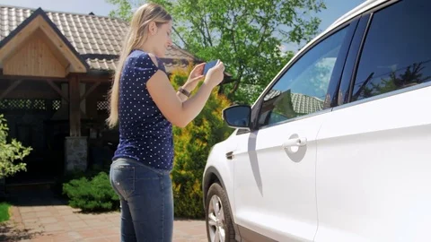 4k footage of young woman making photos of her car on smart phone for selling it Stock Footage
