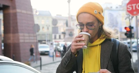 4k. Freelancer or student in the town. Handsome young man in yellow hat walks Stock Footage 98347593