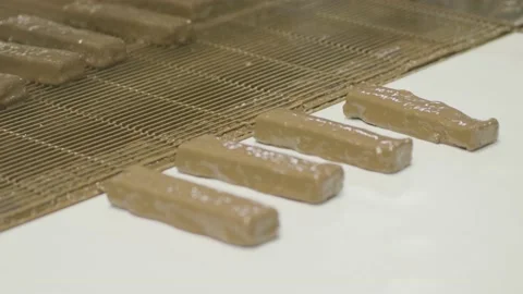 4K Freshly Coated Chocolate Bars Move Along Conveyor Belt Stock Footage 149082596