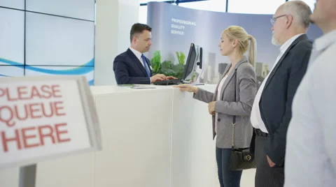 4K Friendly bank worker assisting queue of customers with enquiries Stock Footage 64256758