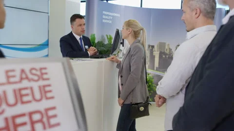 4K Friendly bank worker assisting queue of customers with enquiries Stock Footage 64257236