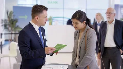 4K Friendly bank workers talking to customers &amp; offering financial advice Stock Footage 64236940