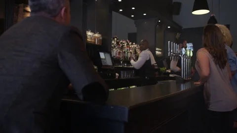 4K Friendly Bar Staff Serving Young Fun Crowd In Fashionable City Bar Video stock 75636228