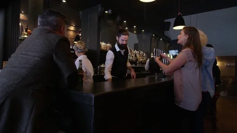 4K Friendly Barman Serving In Bar &amp; Taking Photo Of Group Of Girls On Night Out Video stock 75638651
