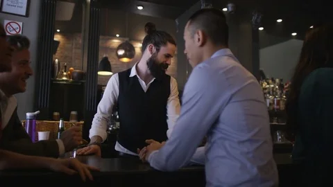 4K Friendly Barman Serving Drinks &amp; Group Of Friends Chatting In City Bar Stock Footage 75802045