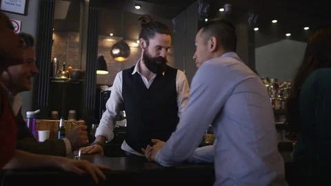 4K Friendly Barman Serving Drinks &amp; Group Of Friends Chatting In City Bar Stock Footage 75802192