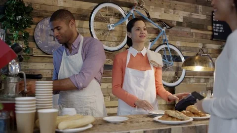 4K Friendly cafe owner couple serving customers &amp; taking contactless payment Stock Footage 76684013