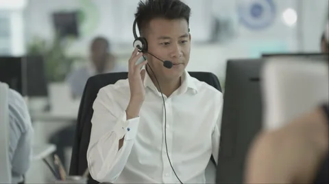 4K Friendly customer service operator talking to customer in busy call centre Stock Footage 64570333
