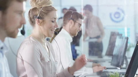 4K Friendly customer service operators taking calls in busy call center Stock Footage