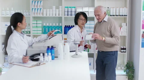 4K Friendly pharmacy worker serving senior man &amp; taking payment  Stock Footage 59083468