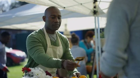 4K Friendly stall holders chatting as they set out produce at farmers market Vidéo 72609604