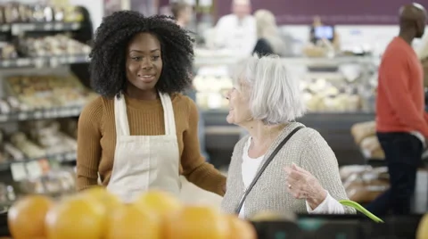 4K Friendly worker in a supermarket assisting senior lady buying groceries Stock Footage 67755905