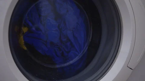 4K front loaded washing machine spinning blue and yellow clothes around Stock Footage 52098857