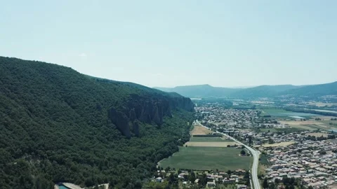4k front tracking shot on rocks overlooking the forest facing a small villag Stock Footage 166020744