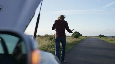 4K Frustrated man on his phone trying to fix his broken down car, in slow motion Stock Footage