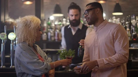 4K Fun Couple Chatting &amp; Bartender Taking Payment For Drinks In City Bar Video stock 75594699