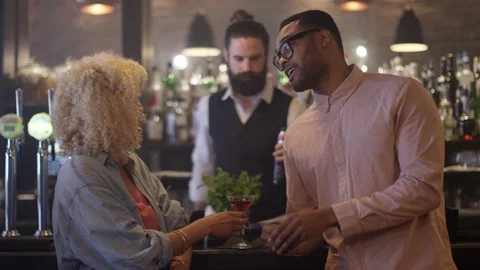 4K Fun Couple Chatting &amp; Bartender Taking Payment For Drinks In City Bar Stock Footage 75595513