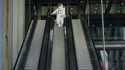 4K Funny astronaut returned to earth, using the escalator in large city building Stock Footage 72607044