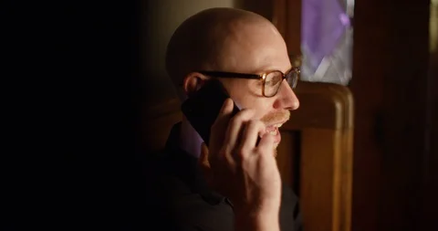 4k Funny priest talking over the phone in between his prayer at his local church Stock Footage 128408045