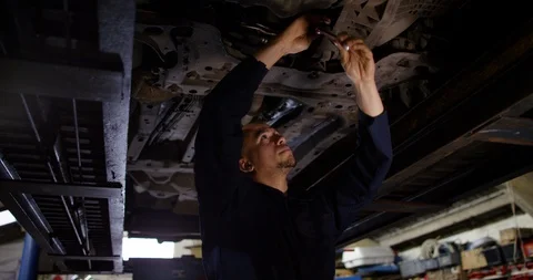 4K Garage mechanic working underneath a vehicle on the ramp in workshop Stock Footage 103046278