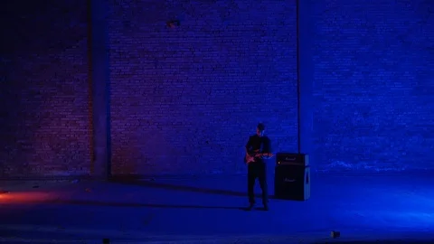 4K General plan in a dark blue garage with a man playing guitar nex to the Stock-Footage 102864717