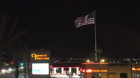 4K - Giant US Flag flies at night over a corner gas station in Las Vegas Stock Footage 63085670
