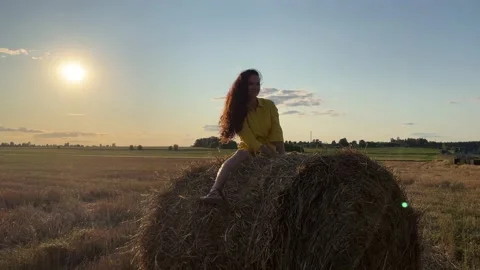 4k Girl swinging on a rolled haystack, shaking hair and dancing. Video stock 161253678