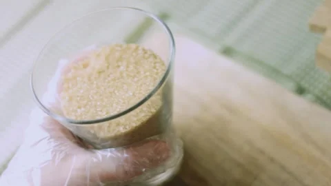 4K Gloved Baker Holding a Measured Glass of Coarse Brown Sugar Stock Footage 342112986