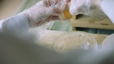 4K Gloved Hands Cracking a Fresh Egg over a Mixing Bowl Stock Footage 342112964