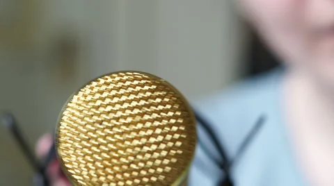 4K Gold microphone shoved in camera, blurred caucasian face speaks aggresivly Stock Footage 62948606