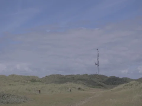 4k grassy hills at coast with structure / building in the distance at noon Video stock 75216631