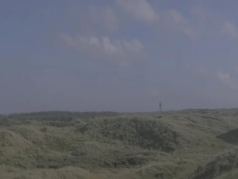 4k grassy hills at coast with structure / building in the distance at noon Video stock 75216710
