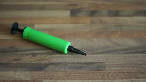 4k Green Balloon Pump rolls and lies still on wooden table top Stock Footage 55287681