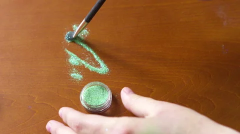 4K Hand brushing green silver makeup glitter together with a black brush Stock Footage 50725810