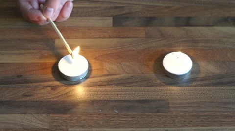 4K hand lighting white tealight candles with a flame from a long wooden match Stock Footage 55287002
