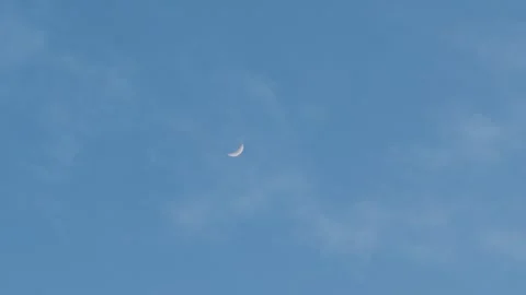 4K Handheld shot of moon against the blue sky with clouds moving in front Stock Footage 325416140