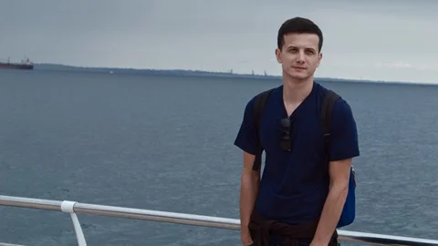 4K A handsom man is standing on a pier and after a while walking away with Vidéo 99932600