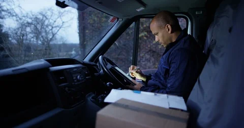4K Handsome delivery driver sitting in truck checking papers &amp; smiling to camera Stock-Footage 85540893
