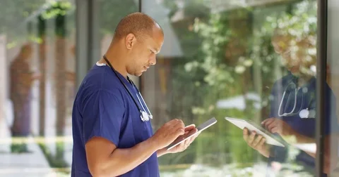 4K Handsome doctor working on digital tablet with his image reflected on window Stock Footage 81178135