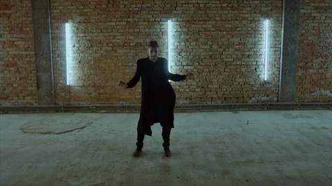4K Handsome young man in black overcoat dances in a garage with back lights Vidéo 102561459