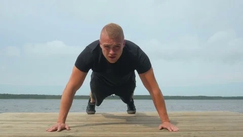 4k of Handsome young man doing push-ups outdoors during training at lake Video stock 83818166