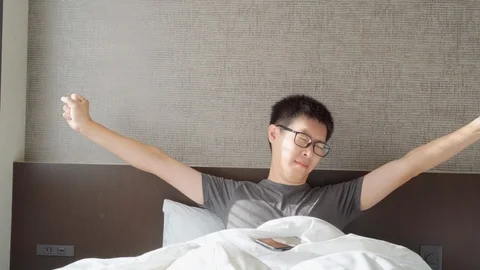 4k Handsome young man using the phone on the bed watching the morning Stock Footage 120456351